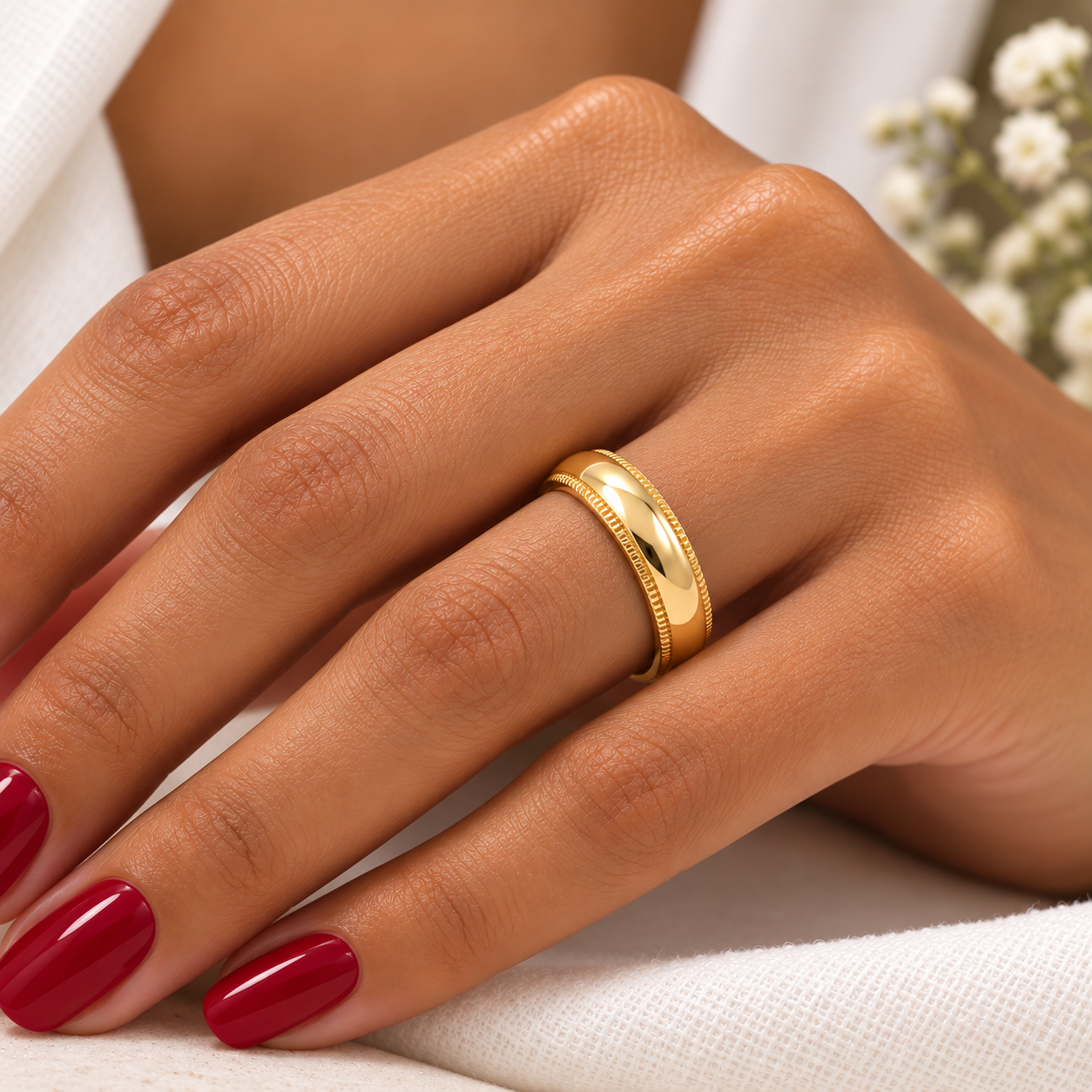 Una argolla 18D653-4LQ en mano de dama con uñas rojas